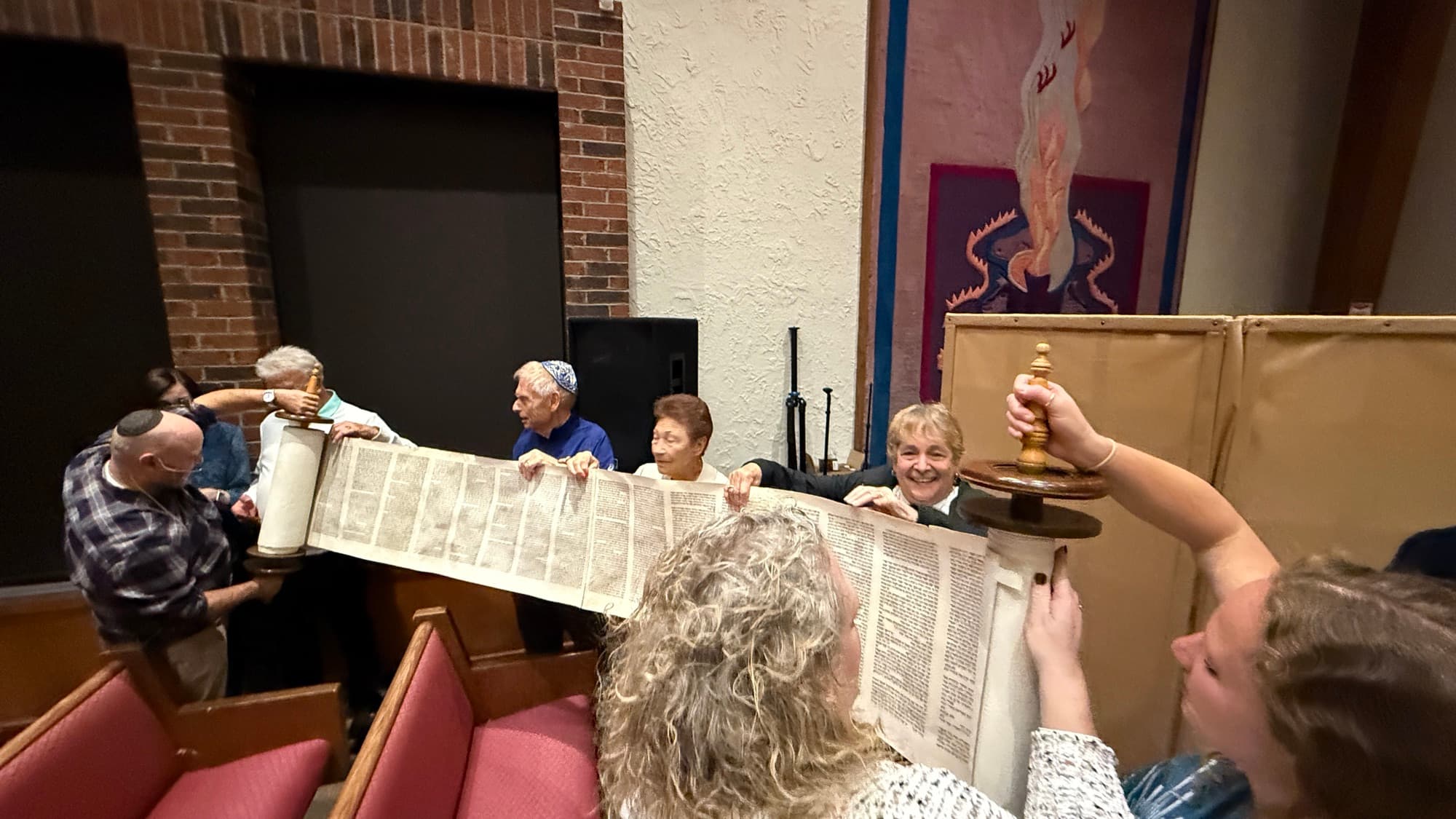 Community members holding the Torah scroll open during a Torah unrolling ceremony