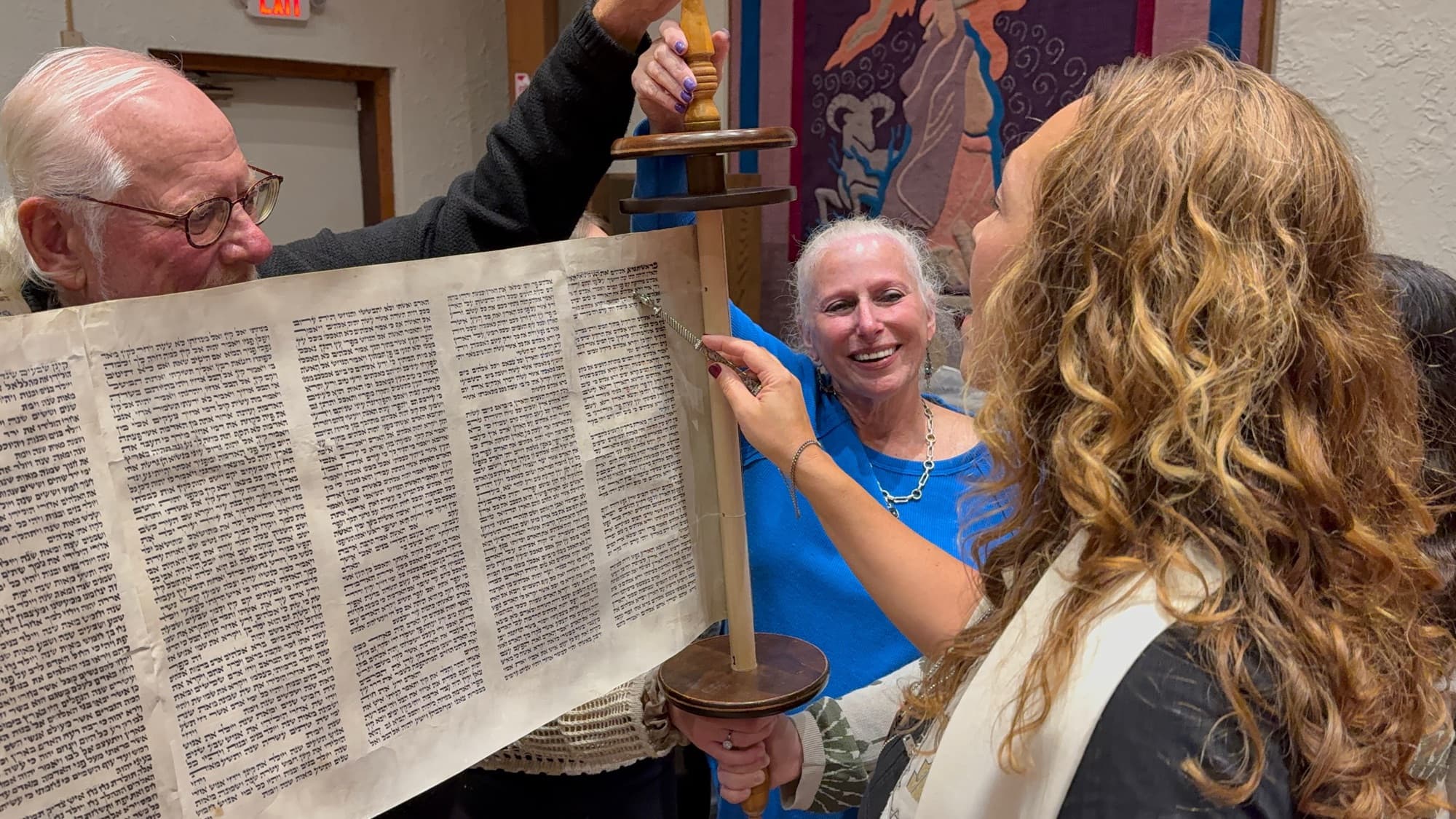 Community members studying the open Torah scroll together