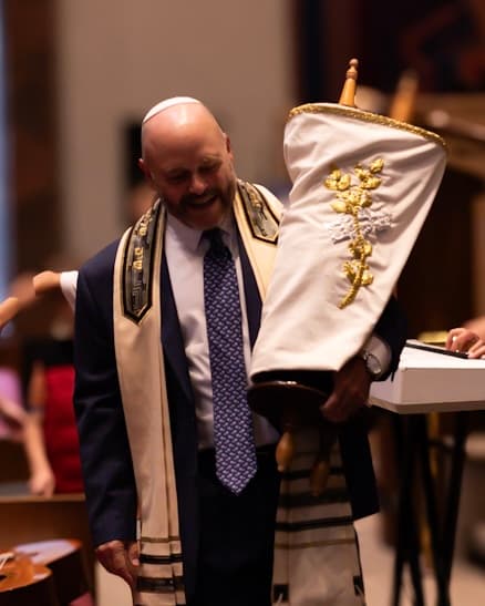 Rabbi Doug smiling warmly while holding the Torah scroll