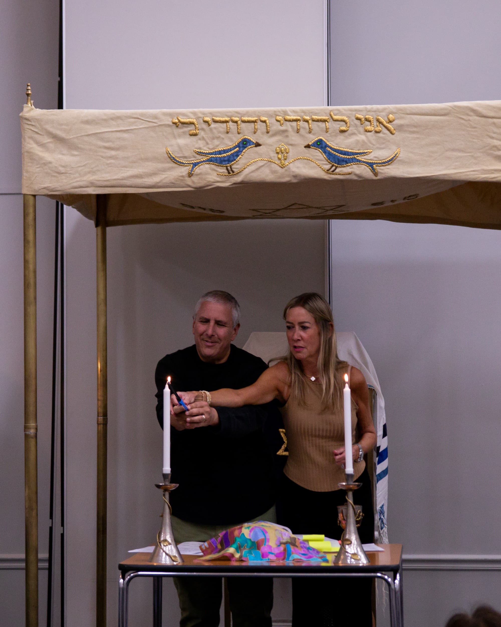 A couple lights Shabbat candles together under the chuppah at Temple Beth Sholom